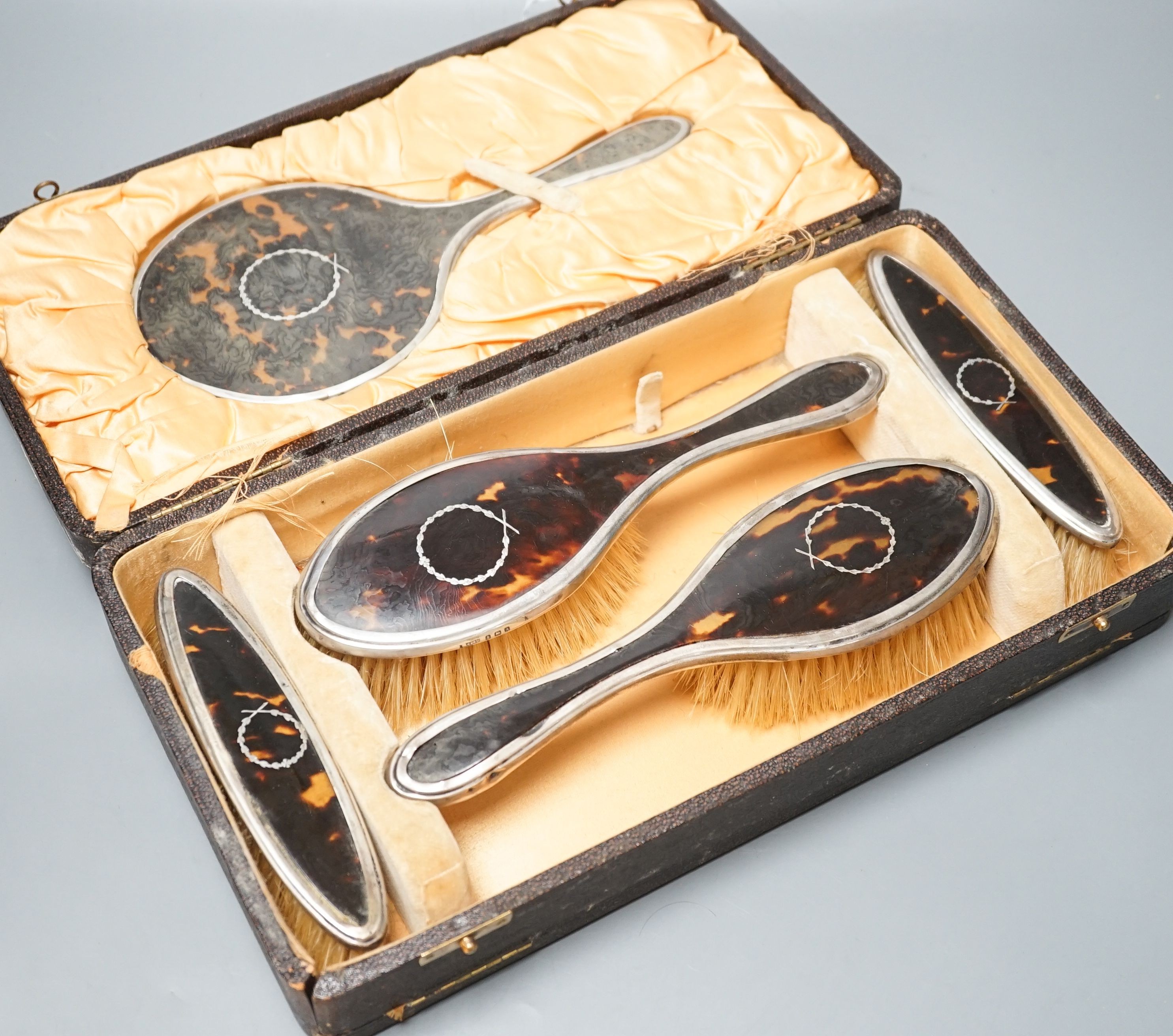 A 1920's cased tortoiseshell and silver mounted mirror and brush set.